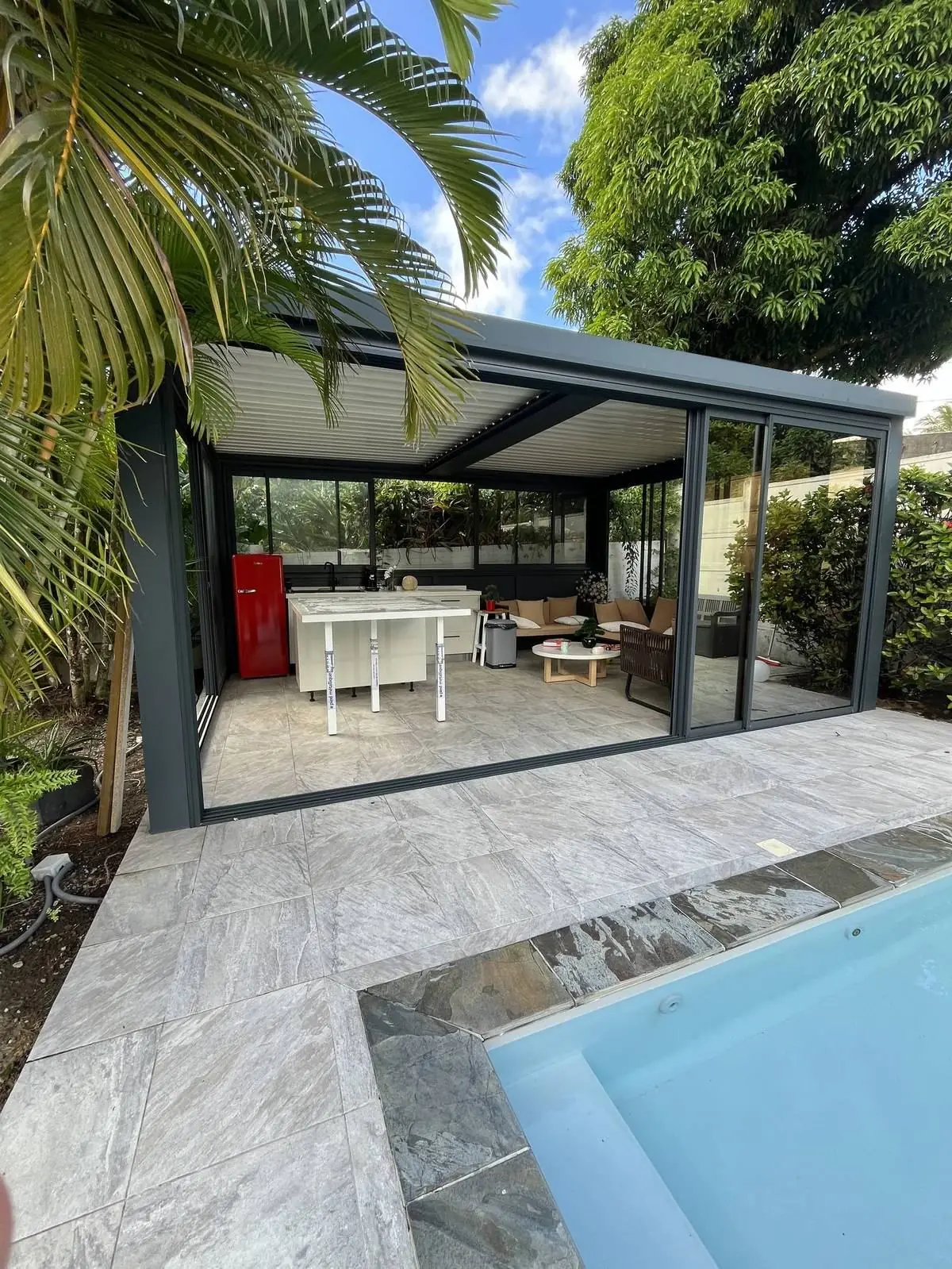 Pergola bioclimatique à lames orientables au bord d'une piscine